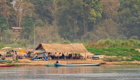 Pak Ou’s tranquil Mekong cliffs in Laos on a Pak Ou Tours banner by Legend Travel Group.